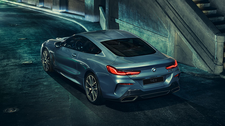 BMW 8 серии Coupe в городе, вид слева сзади с поворотом в три четверти.